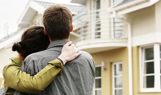 A couple standing in front of their home.